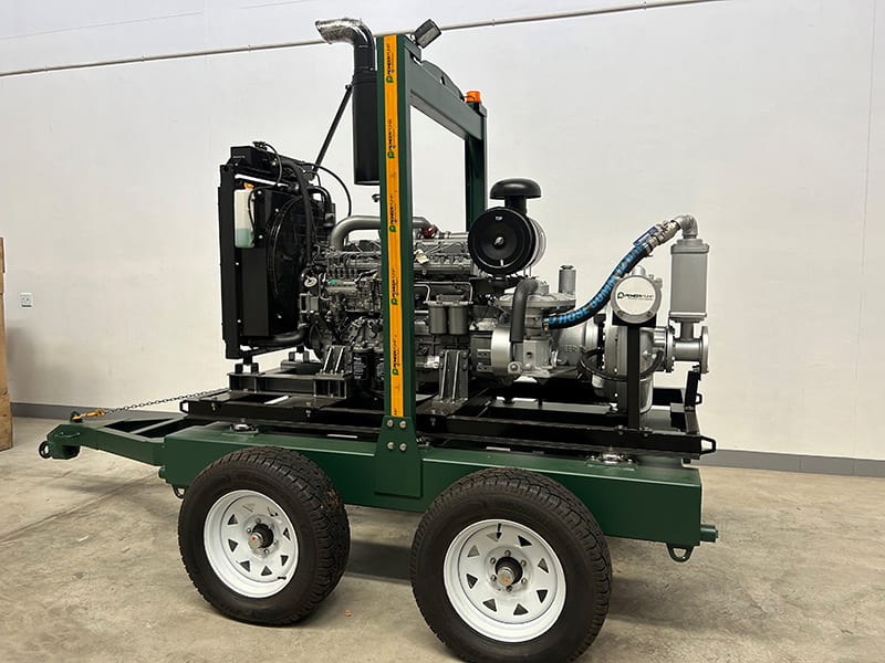 A large, green, portable industrial pump on a two-wheeled trailer with a diesel engine visible.